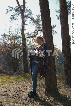 Blonde woman playing guitar ukulele outdoors in autumn forest. Concept of sound therapy, mental health and wellness rituals. Calmness tranquility audio-sensory practices. Aura farming Blonde woman playing guitar ukulele outdoors in autumn forest. Concept of sound therapy, mental health and wellness rituals. Calmness tranquility audio-sensory practices. Aura farming 140821534