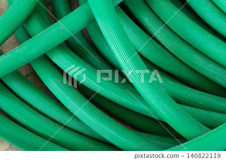 Closeup of coiled green garden hose textured surface creating abstract industrial background suitable for gardening irrigation plumbing maintenance utility concepts Closeup of coiled green garden hose textured surface creating abstract industrial background suitable for gardening irrigation plumbing maintenance utility concepts 140822119