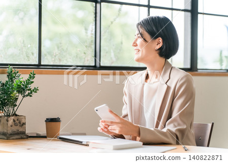 年輕亞洲女商人在咖啡館使用智慧型手機 年輕亞洲女商人在咖啡館使用智慧型手機 140822871