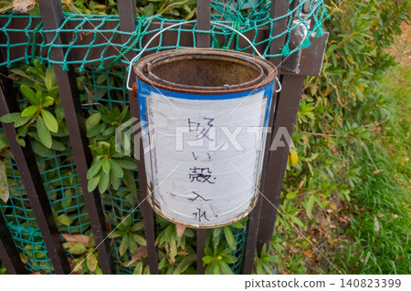 A cigarette butt receptacle hanging from a fence A cigarette butt receptacle hanging from a fence 140823399