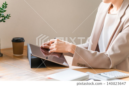 A businesswoman in a suit using a tablet. A businesswoman in a suit using a tablet. 140823647