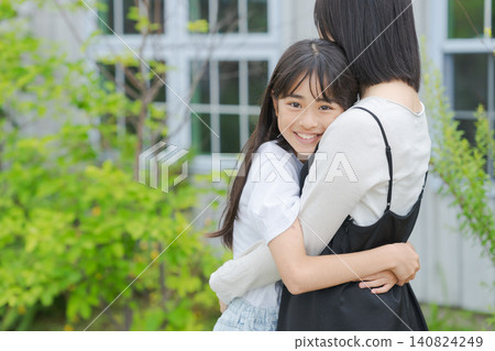 一位母親和她的小學生女兒擁抱在一起。 一位母親和她的小學生女兒擁抱在一起。 140824249