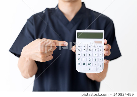 一位身穿藏藍色手術服的中年男醫生指著一台白色計算器。 一位身穿藏藍色手術服的中年男醫生指著一台白色計算器。 140824499
