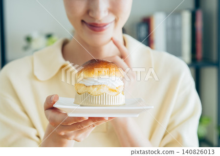 一位年輕女子正在吃朗姆酒薩瓦林蛋糕。 140826013