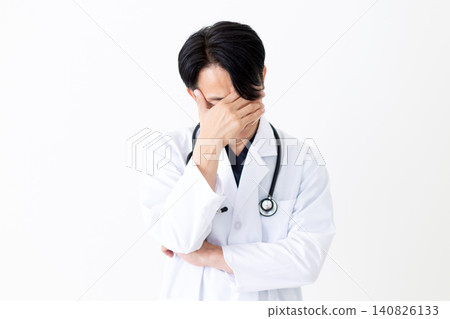 一位身穿白大褂的中年男醫生心事重重。 一位身穿白大褂的中年男醫生心事重重。 140826133