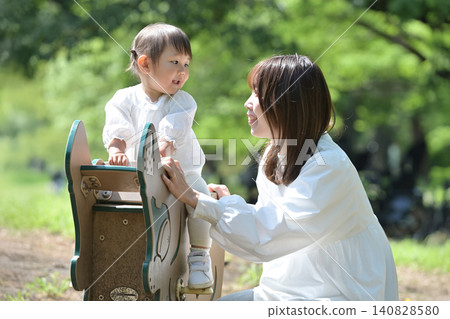 一位母親和女兒在公園裡玩春季遊樂設施。 一位母親和女兒在公園裡玩春季遊樂設施。 140828580
