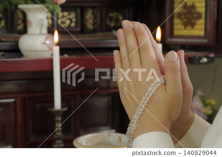 A woman prays with her hands clasped together in front of a Buddhist altar. A woman prays with her hands clasped together in front of a Buddhist altar. 140829044