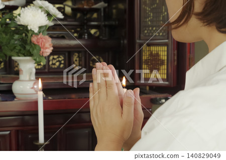 A woman prays with her hands clasped together in front of a Buddhist altar. A woman prays with her hands clasped together in front of a Buddhist altar. 140829049