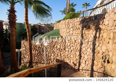 A staircase along a high wall made of large stones A staircase along a high wall made of large stones 140829120