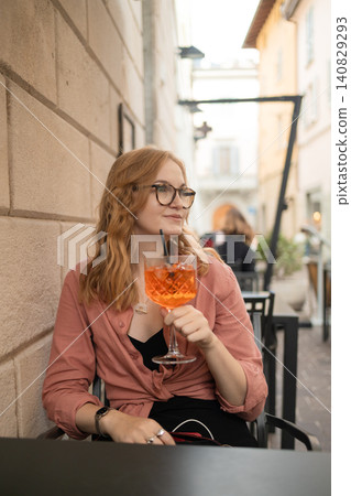 Beautiful young woman sitting at outdoor cafe with Aperol Spritz cocktail on summer vacation 140829293