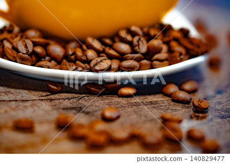 Cup of coffee and coffee beans on a white plate. dark background Cup of coffee and coffee beans on a white plate. dark background 140829477