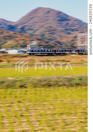 A panning shot captures the autumn scenery of Mt. Futakami and a Kintetsu train, creating a sense of speed. A panning shot captures the autumn scenery of Mt. Futakami and a Kintetsu train, creating a sense of speed. 140830159