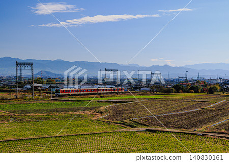 A Kintetsu Railway commuter train speeds through vast rice fields and beautiful scenery. A Kintetsu Railway commuter train speeds through vast rice fields and beautiful scenery. 140830161