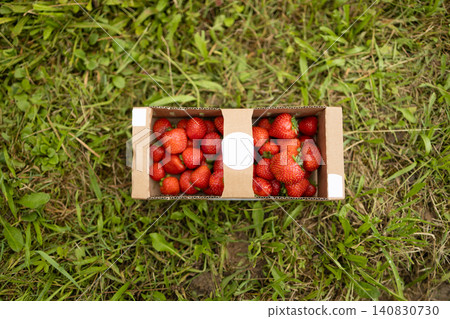 Top view of cardboard box filled with fresh strawberries on grass 140830730