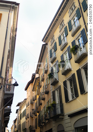 Historical yellow villa building surrounded by green mountains at Como Lake Historical yellow villa building surrounded by green mountains at Como Lake 140830790