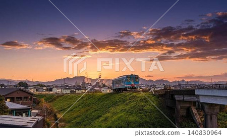 The Tarumi Railway runs against a backdrop of a sunset sky and mountain ranges, creating a beautiful rural landscape (copy space available). 140830964