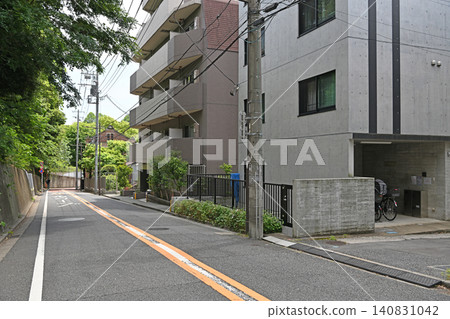 一條安靜的緩坡街道，俯瞰著綠樹成蔭；在谷中、根津和千駄木，一座現代化的公寓大樓矗立在一所歷史悠久的高中前面。 140831042