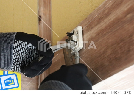 戴著黑色手套進行電氣作業,將兩條電線連接到接線盒上。 戴著黑色手套進行電氣作業,將兩條電線連接到接線盒上。 140831378