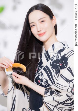 一位身穿浴衣的女子正在做頭髮護理。 一位身穿浴衣的女子正在做頭髮護理。 140831481