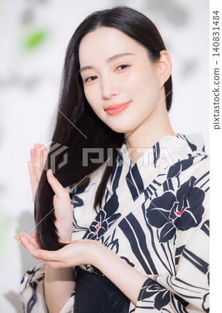 一位身穿浴衣的女子正在做頭髮護理。 一位身穿浴衣的女子正在做頭髮護理。 140831484