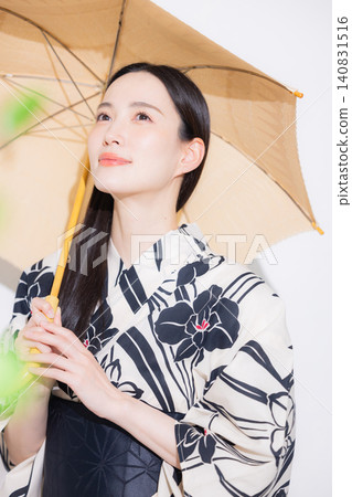 A young woman in a yukata carrying a parasol. 140831516