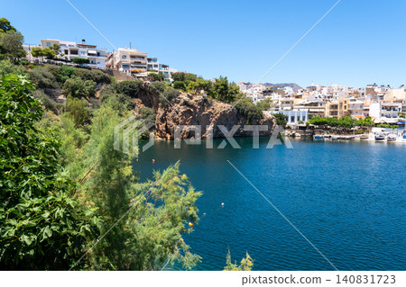 Panoramic view of Lake Voulismeni surrounded by rocky cliffs and town architecture in Agios Nikolaos, Crete, Greece Panoramic view of Lake Voulismeni surrounded by rocky cliffs and town architecture in Agios Nikolaos, Crete, Greece 140831723