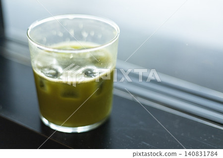 Iced matcha green tea beverage in glass on windowsill 140831784