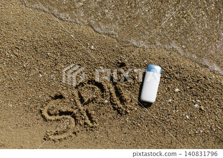 Sun protection factor message in sand with sunscreen bottle on beach by ocean waves 140831796