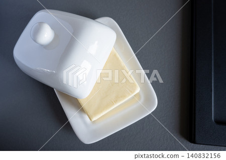 Domestic fresh block of butter in white ceramic box. Baking or cooking ingredient. Domestic fresh block of butter in white ceramic box. Baking or cooking ingredient. 140832156