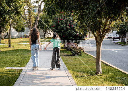 Rear View of Two Friends Skating on Quads and Rollerblades Holding Hands Rear View of Two Friends Skating on Quads and Rollerblades Holding Hands 140832214