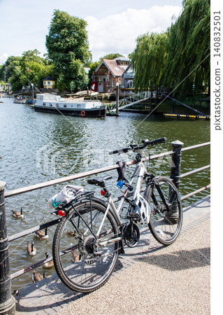 A bicycle parked on a bridge over the Thames River, surrounded by greenery, near Eel Pie Island, on the outskirts of London. A bicycle parked on a bridge over the Thames River, surrounded by greenery, near Eel Pie Island, on the outskirts of London. 140832501