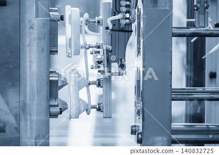 Industrial robotic arm gripping and removing plastic parts from an injection molding machine. Industrial robotic arm gripping and removing plastic parts from an injection molding machine. 140832725