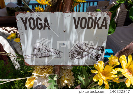 Funny vintage metal sign comparing yoga poses with vodka drinking side effects in an outdoor beach cafe Funny vintage metal sign comparing yoga poses with vodka drinking side effects in an outdoor beach cafe 140832847