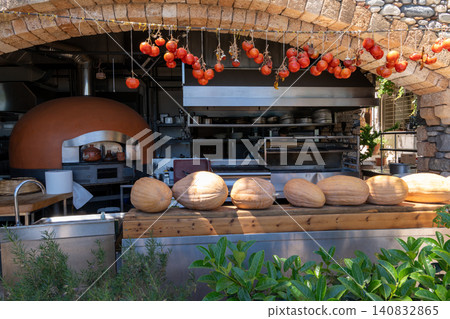 Traditional restaurant open kitchen with stone pizza oven pumpkins and hanging cherry tomatoes Traditional restaurant open kitchen with stone pizza oven pumpkins and hanging cherry tomatoes 140832865