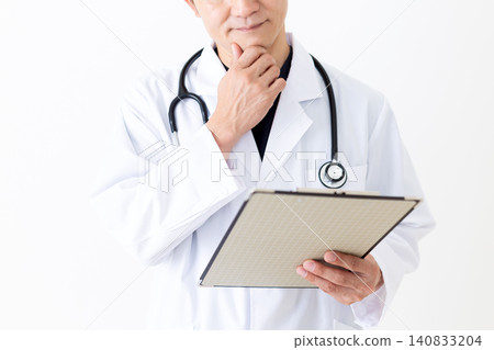 一位身穿白大褂的中年男醫生,手裡拿著一個文件夾,若有所思。 一位身穿白大褂的中年男醫生,手裡拿著一個文件夾,若有所思。 140833204