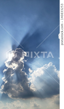 A dramatic summer scene with rays of light radiating from behind cumulonimbus clouds against a clear blue sky. A dramatic summer scene with rays of light radiating from behind cumulonimbus clouds against a clear blue sky. 140833253