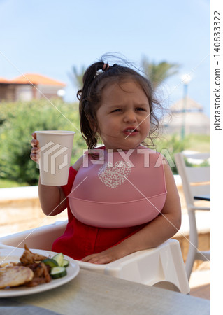 Vertical portrait of cute toddler girl holding paper cup on terrace Vertical portrait of cute toddler girl holding paper cup on terrace 140833322