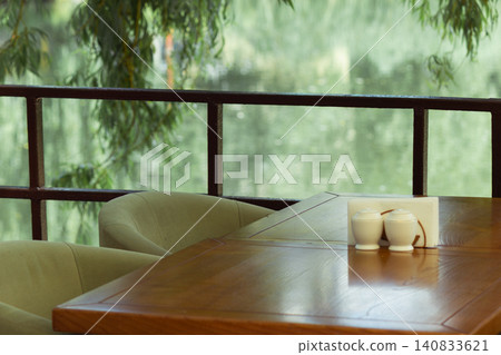 Empty restaurant table with willow branches over a blurred river background Empty restaurant table with willow branches over a blurred river background 140833621