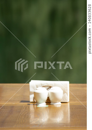 White porcelain spice shakers and paper napkins on wooden table over green background White porcelain spice shakers and paper napkins on wooden table over green background 140833628