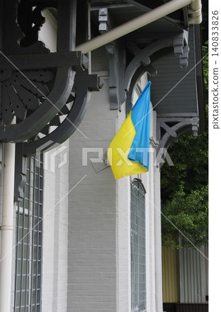 Ukrainian flag displayed on a building exterior, featuring blue and yellow colors, with decorative architectural elements visible in the background Ukrainian flag displayed on a building exterior, featuring blue and yellow colors, with decorative architectural elements visible in the background 140833826
