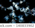 A swarm of iridescent jellyfish glowing in the pitch-black darkness. 140833902