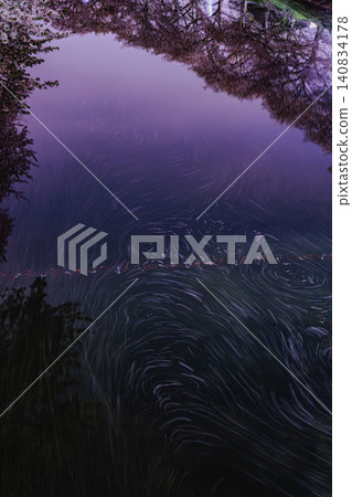 散落的櫻花花瓣優雅地漂浮在水面上,營造出美麗動人的春日景象。 散落的櫻花花瓣優雅地漂浮在水面上,營造出美麗動人的春日景象。 140834178