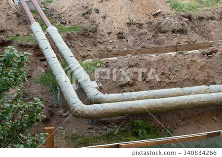 High angle view of insulated utility pipes laid down in a construction site trench for repair works High angle view of insulated utility pipes laid down in a construction site trench for repair works 140834266