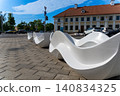 Modern white wave-shaped benches on a paved sidewalk 140834325