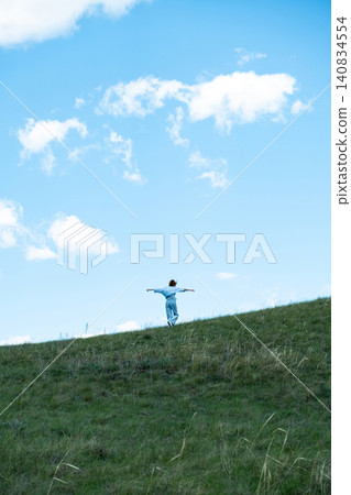 Woman Walking in a Green Field on Rolling Hills, Embracing Freedom and Nature Woman Walking in a Green Field on Rolling Hills, Embracing Freedom and Nature 140834554