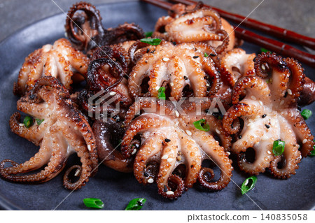 Grilled baby octopus, served with chopsticks, on a black plate, homemade, no people, Grilled baby octopus, served with chopsticks, on a black plate, homemade, no people, 140835058