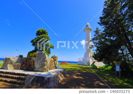 A white lighthouse stands out against the blue sky in early summer in Sado. A white lighthouse stands out against the blue sky in early summer in Sado. 140835273