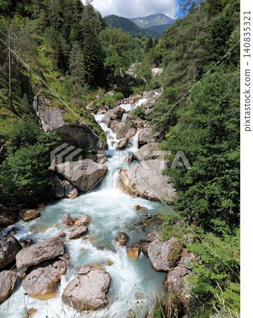 A fast-flowing mountain stream cascading over large boulders in a canyon. A fast-flowing mountain stream cascading over large boulders in a canyon. 140835321