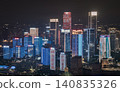 At night, Chongqing becomes a futuristic wonderland of light and shadow. Towering skyscrapers pierce the sky, their glass facades shimmering with cascading LEDs. Vibrant ribbons of neon bleed into the 140835326