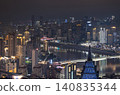 At night, Chongqing unfolds as a dense vertical metropolis of gold and shadow.  countless high-rises stack tightly across the cityscape, their windows glittering with warm golden light. Two distinct 140835344
